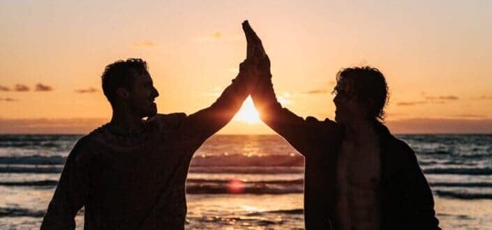 Two guys having fun by the beach while sun sets