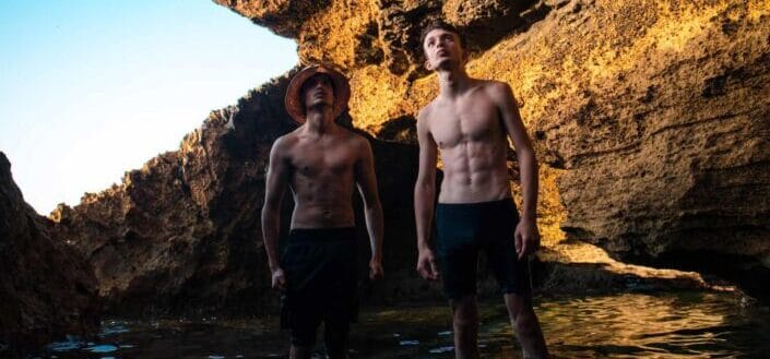 Two topless men looking up on something