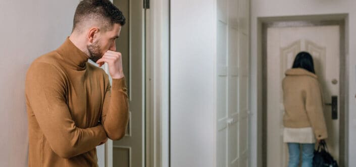 Man looking while a woman walks out the door