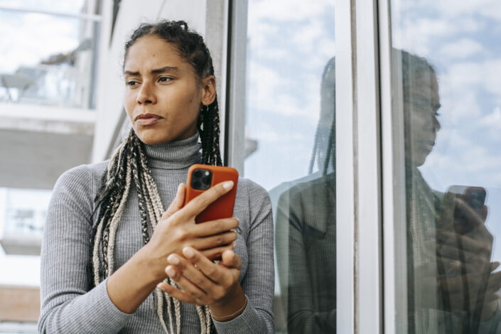 Woman deeply thinking while holding her phone