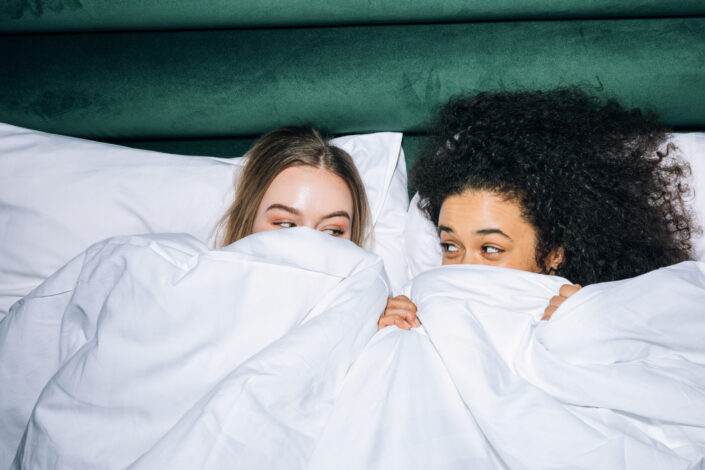 Two girls hiding behind white bed sheets