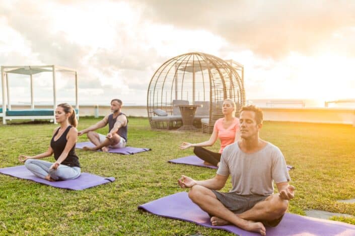 Man and his friends doing yoga outdoors.