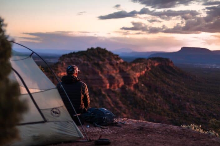 Man camping on top of a mountain.