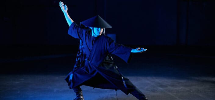 Man performing kung Fu acts while wearing costume.