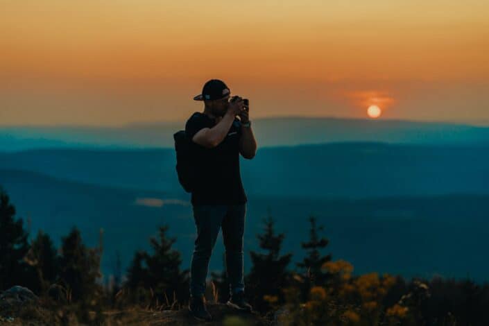 Man on top of a mountain taking pictures of the overview.