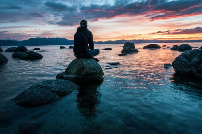 Man sitting on stone and looking at the sunset