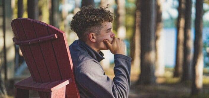 Man sitting on a wooden chair while thinking.