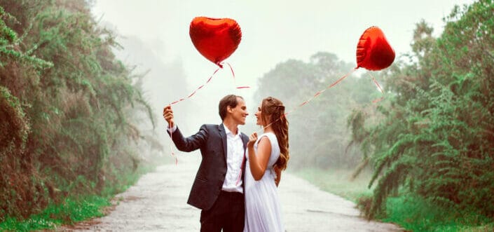 Sweet couple holding a balloon in the middle of the road.