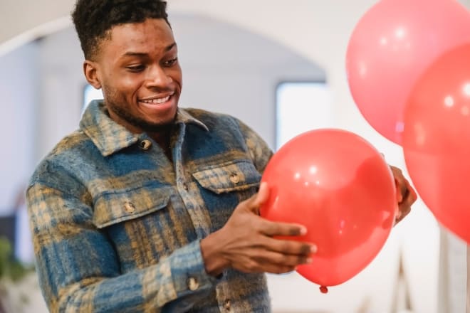 valentines day decor - Smiling black man holding red balloon