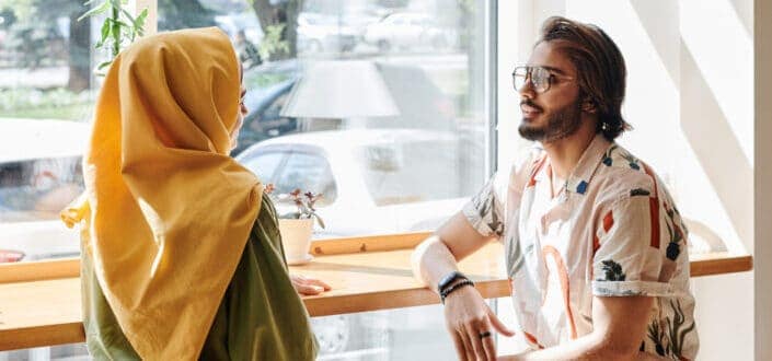 Two people talking to each other while sitting beside a window