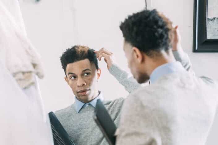 Man fixing his hair in front of the mirror