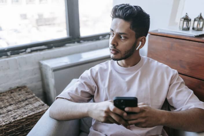 Man with earbuds browsing smartphone