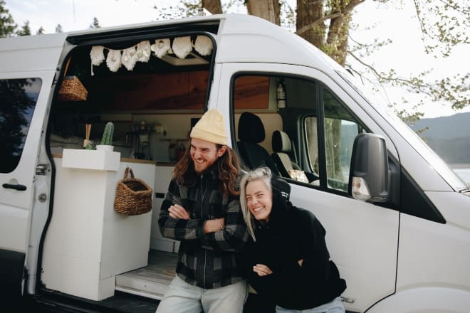 Fun Things To Do On A Date - Couple Laughing While Leaning on a Campervan