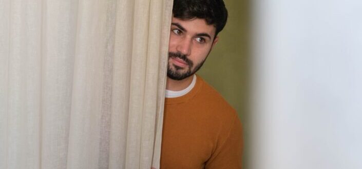 Man hiding behind a curtain