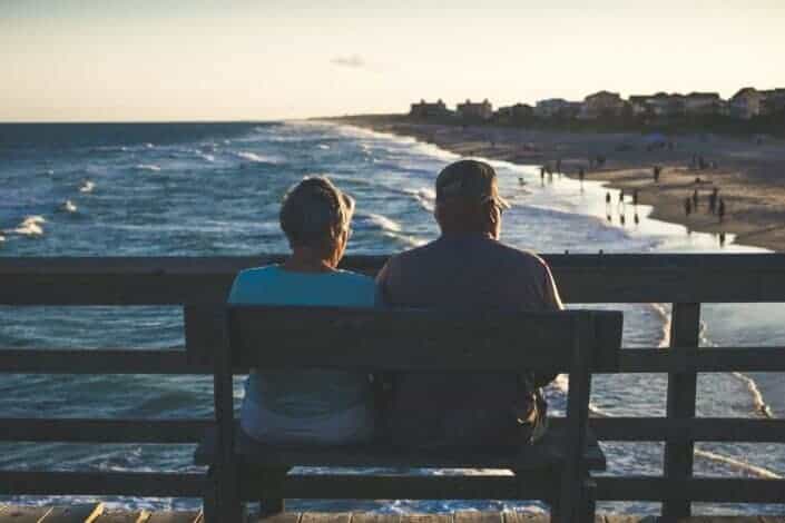 Couple sitting on a bench in front of the beach