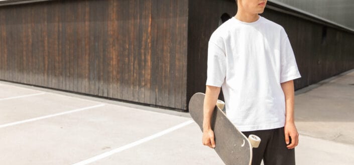 Stylish young Asian male with skateboard in hand