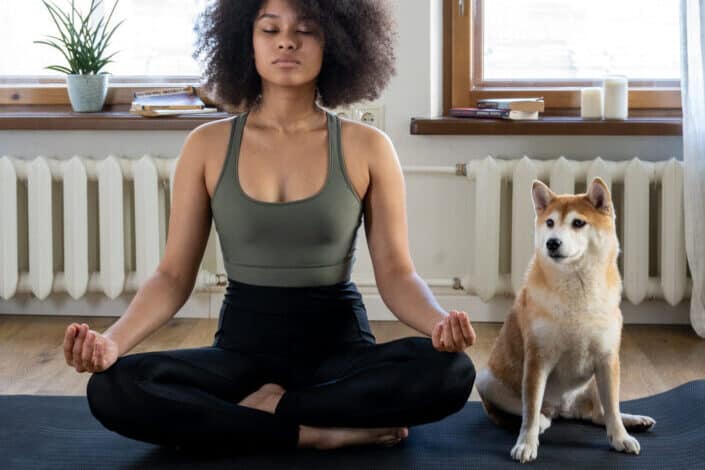 woman doing meditation beside her dog