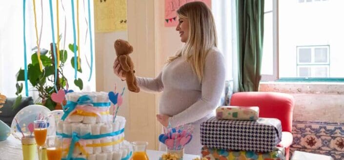 An excited pregnant woman looking at stuffed bear