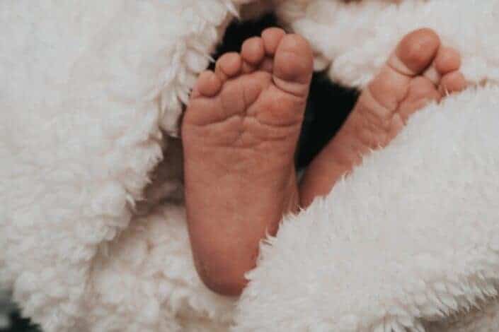 Two tiny feet of an infant covered with blanket