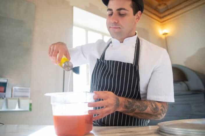 Man in striped apron pouring oil into bowl