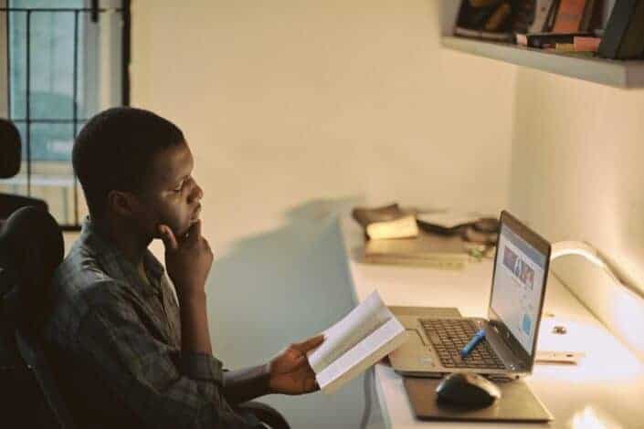 portrait-of-a-creative-african-man-taking-a-break-from-work-to-read-with-his-workspace-blurred-in-the-background-stockpack-unsplash