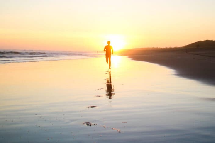 Man on a Beach Running Towards the Sunset