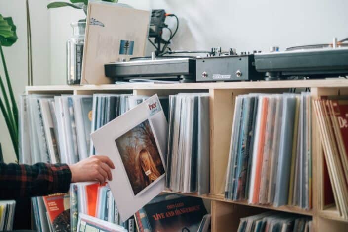 young-man-holding-a-vinyl-album-cover-in-front-of-his-collection-stockpack-unsplash