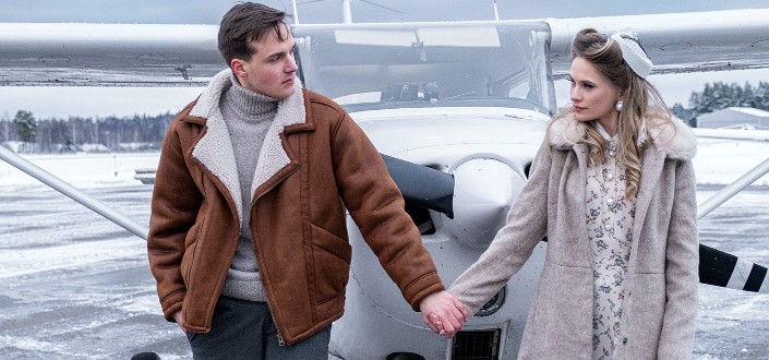 A man and a lady in coats hold hands.