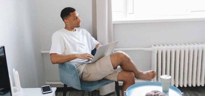 Guy Holding a Laptop Sitting on a Couch