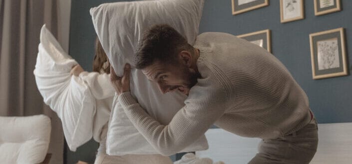 A couple having fun playing pillow fight