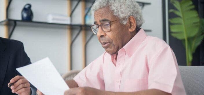A man in pink button up shirt reading a document