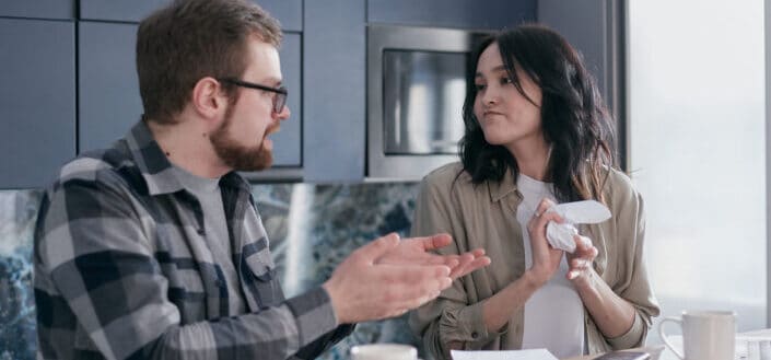 A woman looking at her partner while crumpling a paper