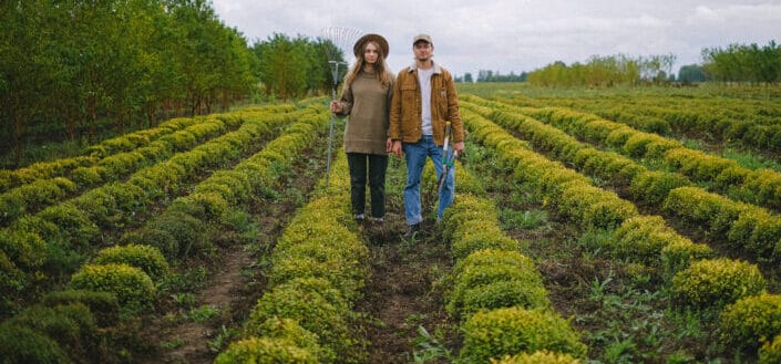 Couple with farm tools standing in field