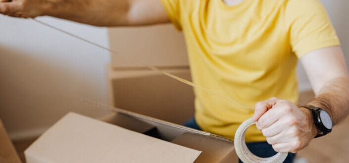 Crop man with cardboard boxes while packing belongings