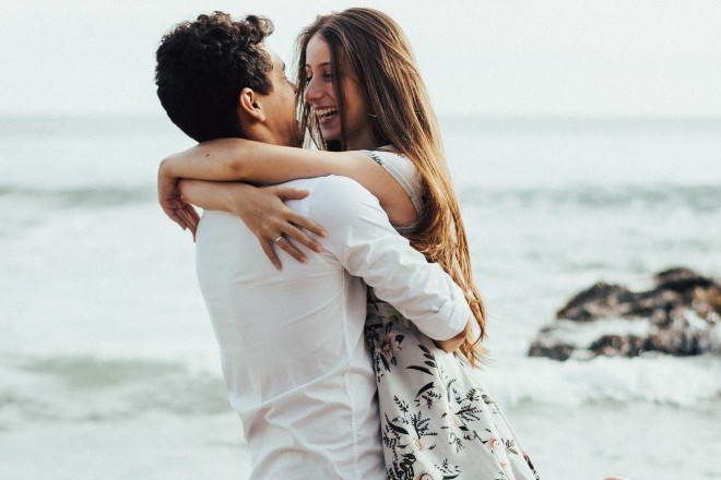 Man lifting woman near beach - signs you are inlove