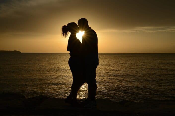 silhouette couple kissing against the sun