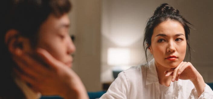 Thoughtful young ethnic women having conversation at table at home