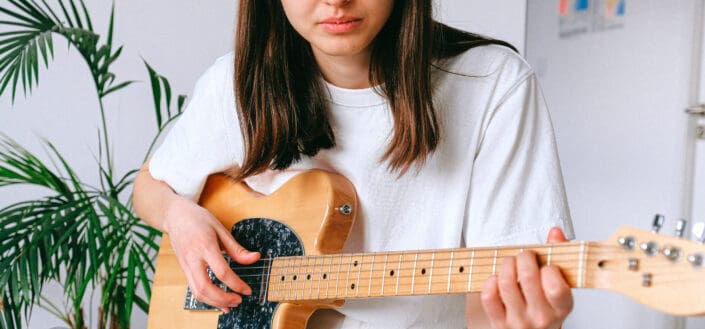 Woman in White Shirt Playing Electric Guitar