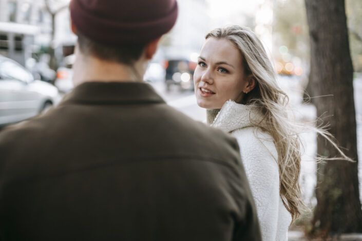 Young woman talking to man on street