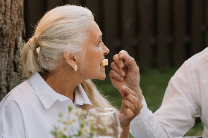 A woman dressed in white eating cheese