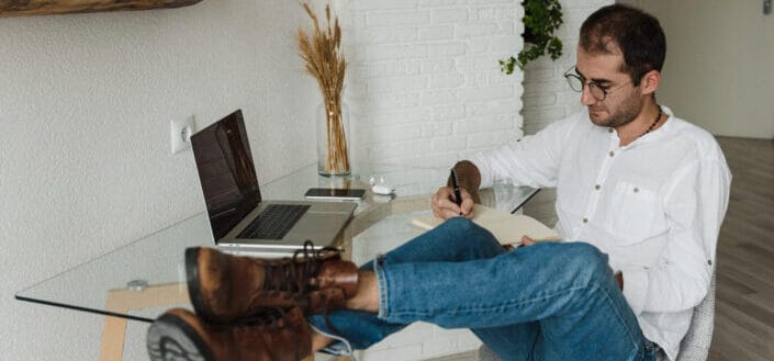 Man Writing With His Feet up on His Desk