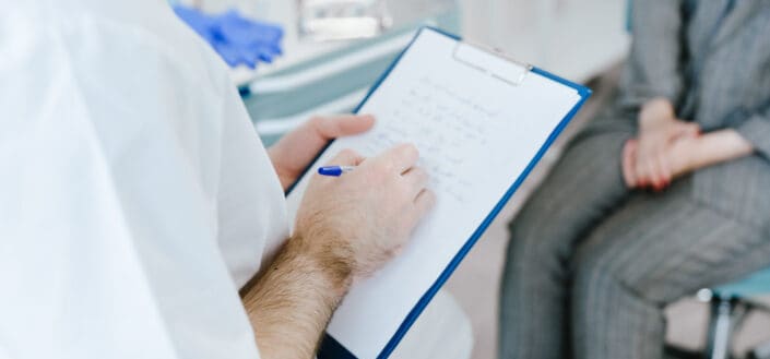 Person Taking Notes While Talking to Patient