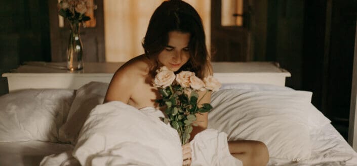 woman holding flowers on bed