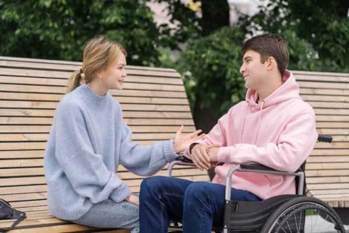 A woman talking to a man sitting on the wheelchair