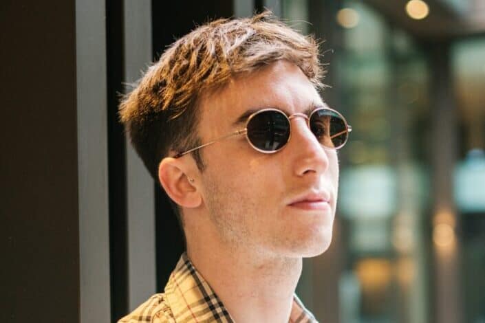 Man with glasses posing near building