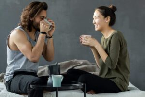 man and woman sitting on the bed having coffee (1)