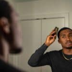man combing his hair in front of a mirror