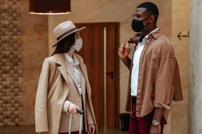 Man with a brown bag talking to woman in beige coat
