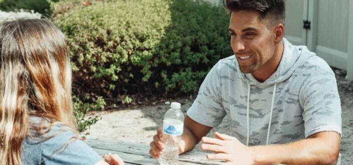 man talking to a lady while holding water bottle