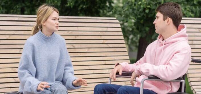 man sitting in wheelchair talking to woman